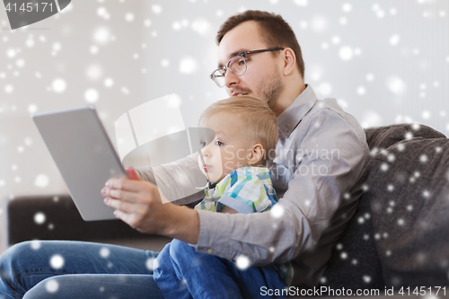 Image of father and son with tablet pc playing at home