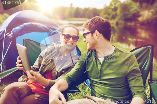 Image of happy couple with tablet pc at camping tent