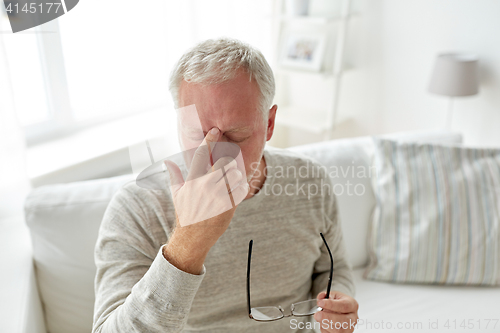 Image of senior man suffering from headache at home