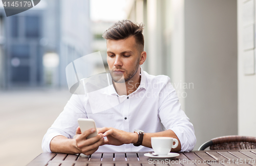 Image of man with smartphone and coffee at city cafe