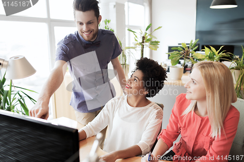 Image of happy creative team with computer in office