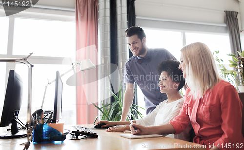 Image of happy creative team with computer in office
