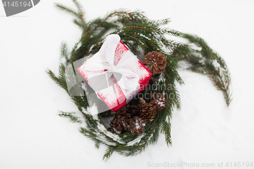 Image of christmas gift and fir wreath with cones on snow