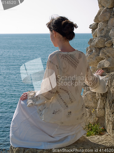 Image of Lonely Young Woman on Stone Looking to Sea