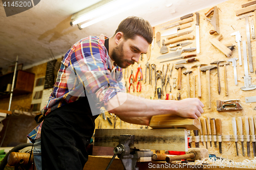 Image of carpenter working with plane and wood at workshop