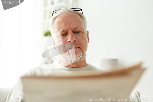 Image of close up of senior man reading newspaper at home