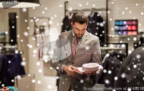 Image of happy young man choosing shirt in clothing store