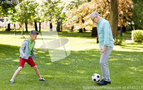 Image of old man and boy playing football at summer park