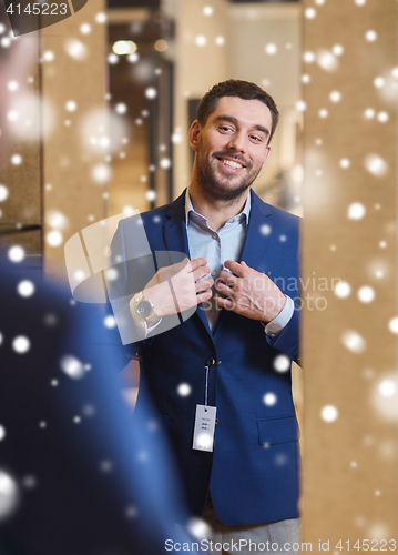 Image of man trying jacket on at mirror in clothing store