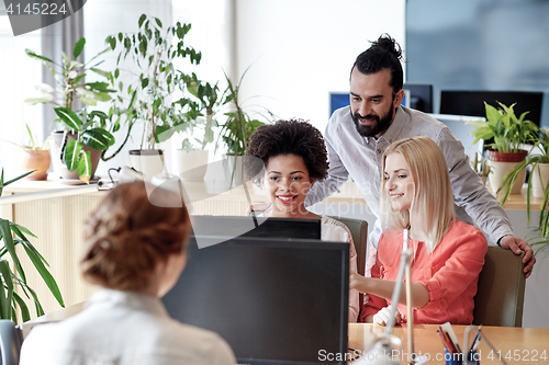 Image of happy creative team with computer in office