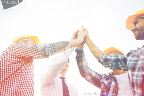 Image of close up of builders in hardhats making high five