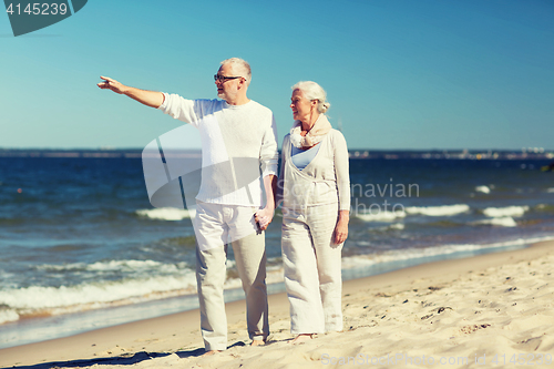 Image of happy senior couple walking on summer beach