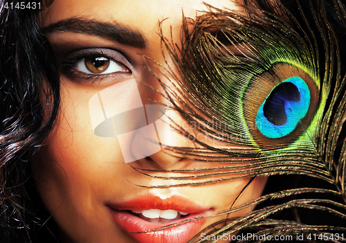 Image of young sensitive brunette woman with peacock feather eyes close u