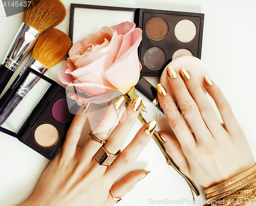 Image of woman hands with golden manicure and many rings holding brushes,