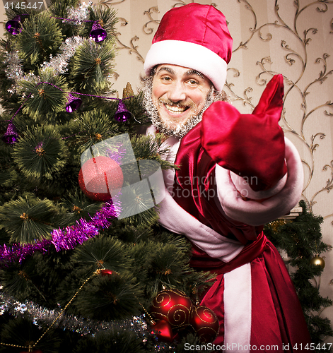 Image of portrait of funny Santa Claus at home with christmass tree