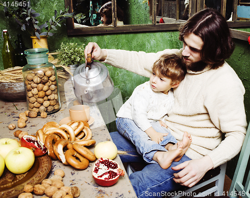 Image of father with beard holding son at countryside vintage kitchen close up