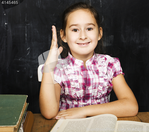 Image of cute little real girl pupil in classroom at blackboard writting, girl school, ready to answer