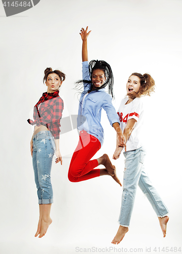 Image of three pretty african american and caucasian, brunette and blonde teenage girl friends jumping happy smiling on white background, lifestyle people concept