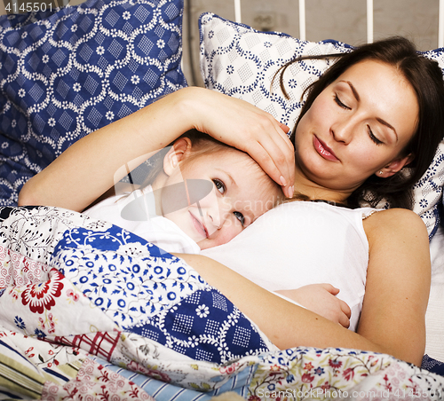 Image of Portrait of mother and daughter laying in bed and smiling