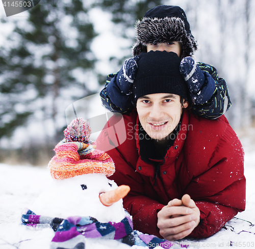 Image of portrait of happy father with his son outside with snowman, lifestyle people concept
