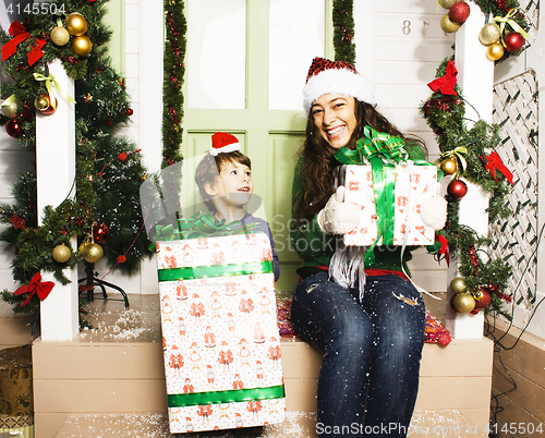Image of happy family on Christmas in red santas hats waiting gests and smiling infront of decorated house, mother and son, lifestyle people concept