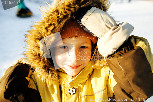 Image of little cute boy in hood with fur on snow outside