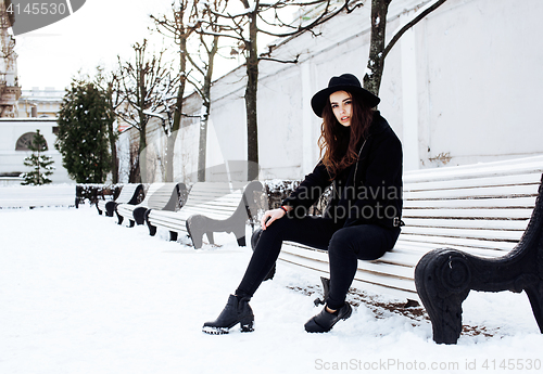 Image of young pretty modern hipster girl waiting on bench at winter snow park alone, lifestyle people concept