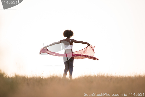 Image of black girl dances outdoors in a meadow