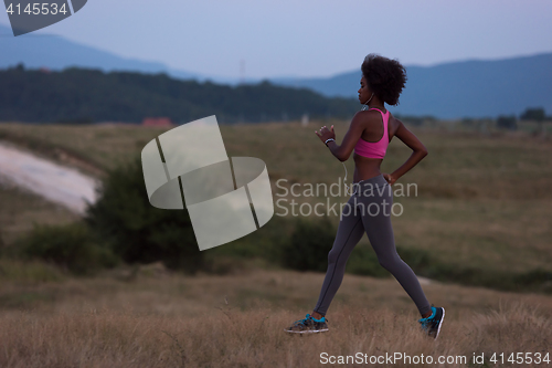 Image of Young African american woman jogging in nature