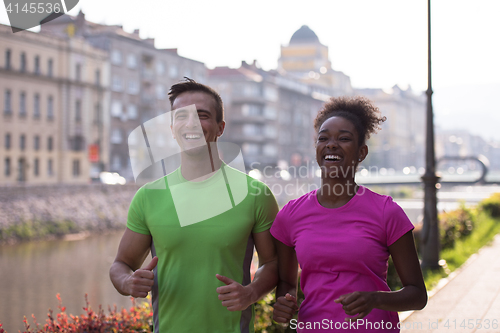 Image of young multiethnic couple jogging in the city