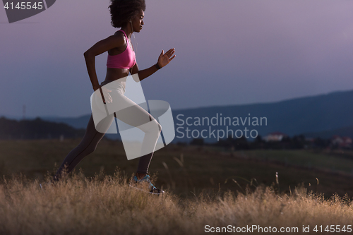 Image of Young African american woman jogging in nature