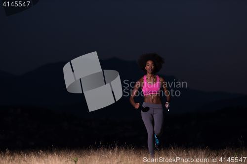 Image of Young African american woman jogging in nature