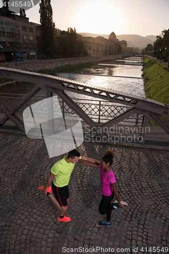 Image of jogging couple warming up and stretching in the city