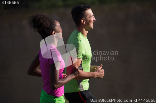 Image of young smiling multiethnic couple jogging in the city