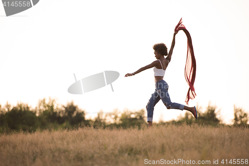 Image of black girl dances outdoors in a meadow