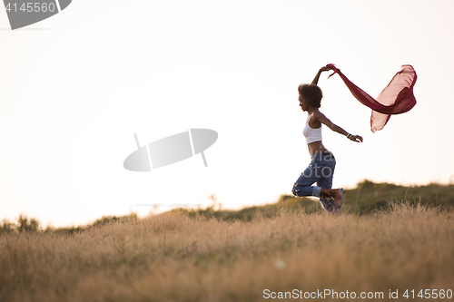 Image of black girl dances outdoors in a meadow