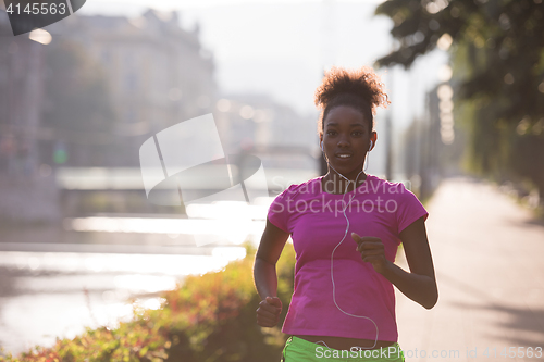 Image of african american woman jogging in the city