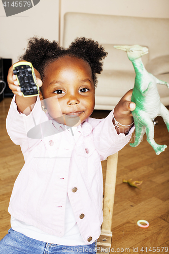 Image of little cute african american girl playing with animal toys at ho