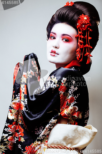 Image of young pretty geisha in black kimono among sakura, asian ethno