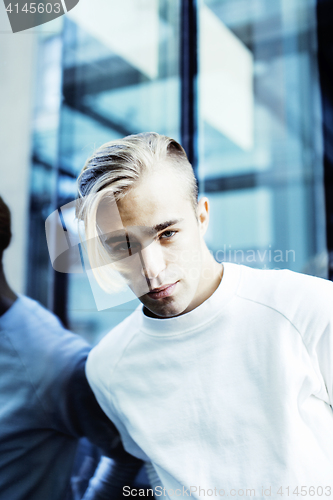 Image of young modern hipster guy at new building university blond fashio