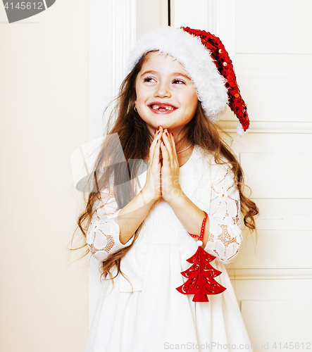 Image of little cute girl in santas red hat waiting for Christmas gifts. 