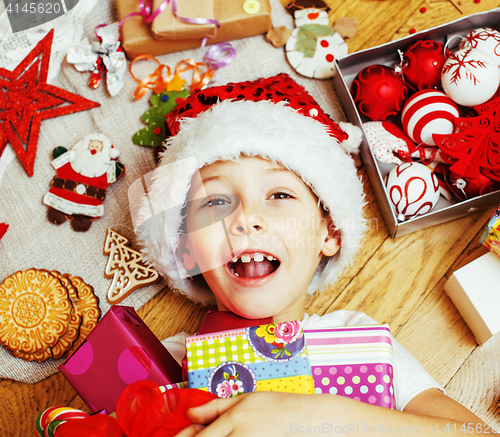 Image of little cute kid in santas red hat with handmade gifts, toys vintage wooden, warm winter