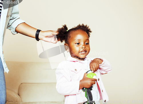 Image of modern young happy african-american family: mother combing daughters hair at home, lifestyle people concept