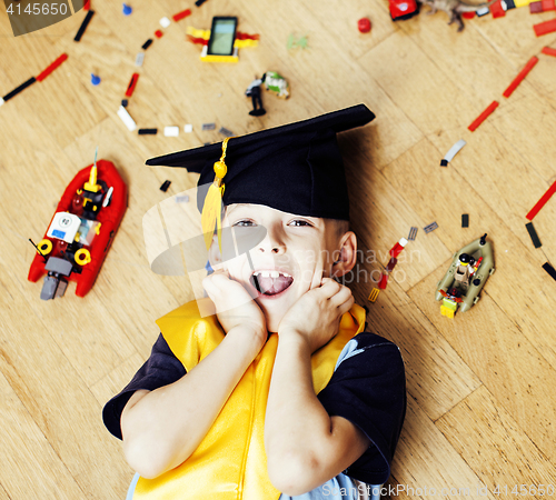 Image of little cute preschooler boy among toys lego at home in graduate hat, educational people concept