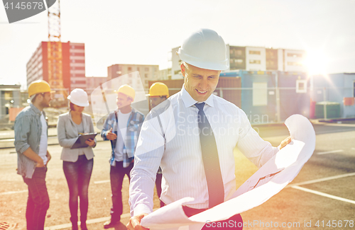 Image of architect with blueprint on construction site