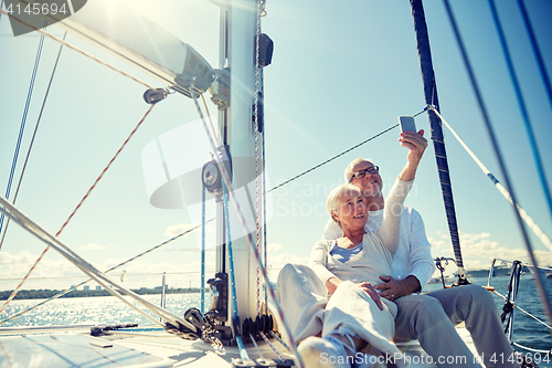 Image of seniors with smartphone taking selfie on yacht