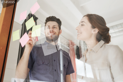 Image of creative team with stickers on glass at office