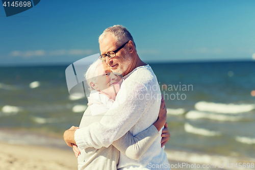 Image of happy senior couple hugging on summer beach