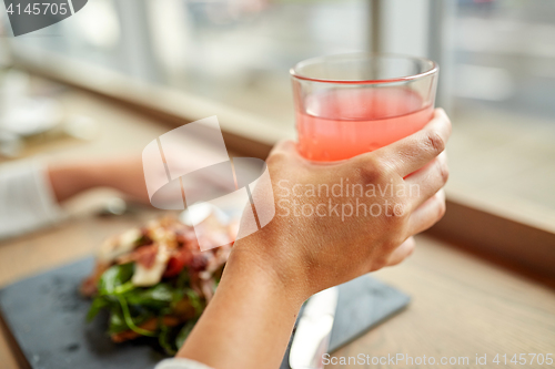 Image of hand with glass of juice and salad at restaurant