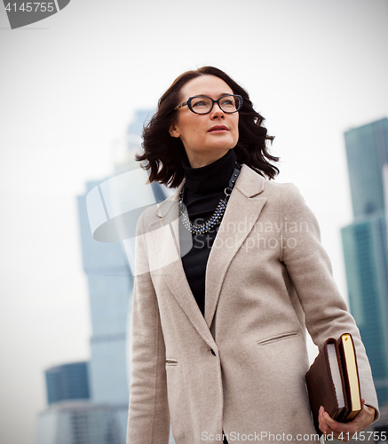 Image of Smiling dark-haired businesswoman in a bright coat
